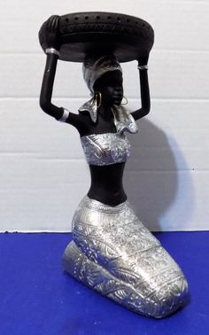 a figurine is holding a tire on her head and wearing a silver dress