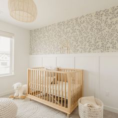 a baby's crib in the corner of a room with floral wallpaper