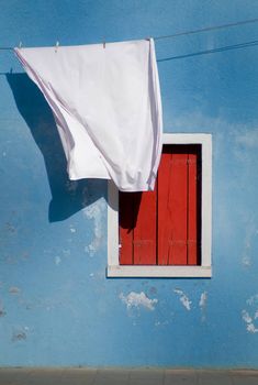 a blue wall with a red door and white sheet hanging from it's side