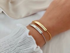 a woman's arm with two gold bracelets on it and the word always is written in cursive font