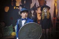 a man in a top hat and bow tie holding a satellite dish with other people behind him