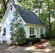 a small white house surrounded by trees in the woods