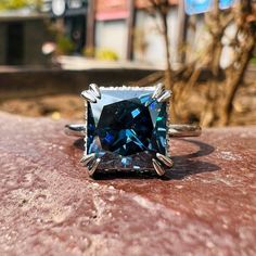 a blue diamond ring sitting on top of a rock