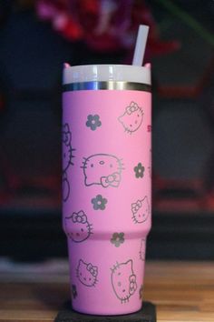 a pink cup with hello kitty on it and a straw sticking out of the lid