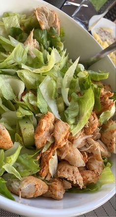 a white bowl filled with lettuce and chicken