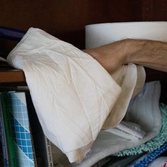 a man's arm wrapped in white cloth next to a book shelf filled with books