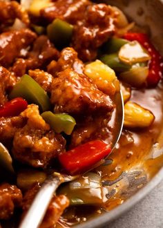 a bowl filled with meat and vegetables next to a spoon