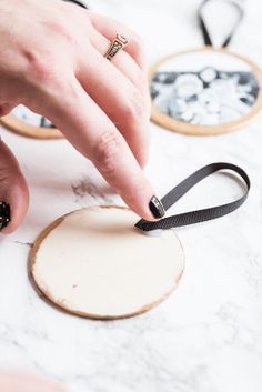 a person is using a black ribbon to tie something on a piece of wood with scissors