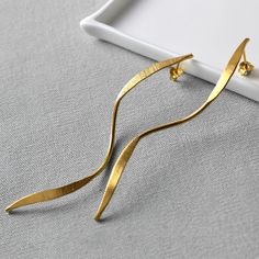 "These elongated gold ribbons are the perfect statement earrings. Light to wear with maximum visual impact these are a sublime evening earring.  With the appearance of movement even when still, these beautiful earrings will make the perfect gift. So if you're heading out with the girls or want to make waves at a wedding these earrings are ideal. Almost skimming the collar these elegant earrings are subtle yet eye catching. With fashion bloggers raving about their style and and waterfall vibe everyone will be asking \"where did you get them?\"  Whether they're a treat for you or someone special everyone will notice these dynamically different earrings." Elegant Yellow Gold Wrap Earrings For Party, Modern Gold Wrap Earrings For Formal Occasions, Elegant Gold Linear Earrings For Evening, Elegant Drop Earrings For Evening, Elegant Drop Wrap Earrings For Evening, Chic Gold Wrap Earrings For Formal Occasions, Gold Drop Wrap Earrings For Formal Occasions, Modern Gold Linear Earrings For Evening, Elegant Gold Wrap Earrings For Anniversary