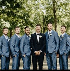 a group of men standing next to each other wearing suits and ties with trees in the background