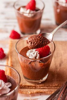 chocolate mousse with whipped cream and raspberries in a small glass bowl