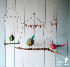 three colorful birds sitting on top of a tree branch next to some string hanging from the ceiling