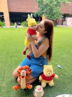 a woman sitting on the grass with winnie the pooh and tigger