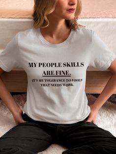 a woman is sitting on the floor with her hands in her pockets and wearing a t - shirt that says, my people skills are fine