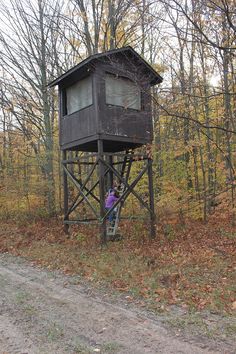 a man climbing up the side of a tall wooden tower in the middle of a forest