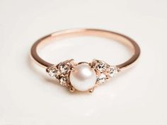 a pearl and diamond ring on a white surface