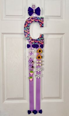 a door hanger with the letter g on it, decorated with flowers and bows