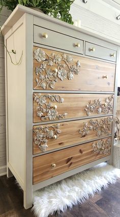 an old dresser has been painted white and gold with flowers on the drawers, along with faux sheepskin rugs