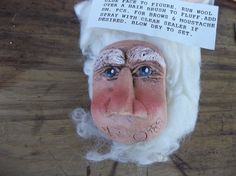 a close up of a fake santa claus head on a wooden table next to scissors