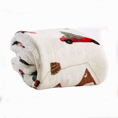 a white blanket with red and green christmas decorations on it, folded up in front of a white background