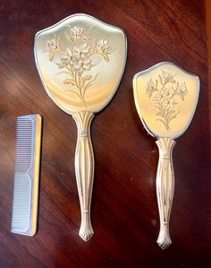 Stunning vintage vanity hand held mirror, brush and comb in a gorgeous art deco brushed gold tone and floral embellishments on brass handles.  Please see all photos before purchasing. These 3 pieces are in good vintage condition.  l'm happy to combine shipping if you purchase more than one item in any of my shops.  All items shipped with care using recycled or repurposed materials.  Thank you for visiting Nesting with Noel, my little shop of treasures. Each piece has been procured for those that also love vintage items and are interested in sustainability. There's a limit to what I can keep for myself so my passion is offering others unique treasures in their own nests. Please browse my other vintage pieces and, if you're so inclined, click on favorite.  Like this item? Visit my shop for m Cute Vanity Decor, Art Deco Vanity Mirror, Hand Held Mirror, Vintage Comb, Brush And Comb, Art Deco Vanity, Antique Vanity, Art Deco Floral, Room Goals