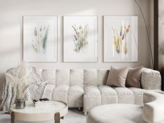 a living room filled with white furniture and paintings on the wall above it's coffee table