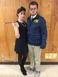 the man and woman are posing for a photo in front of a wooden wall with a sign on it