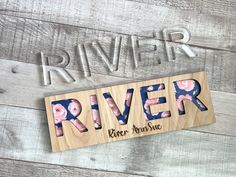 a wooden sign that says river with flowers on it and the word river written in wood