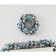 a christmas wreath is hanging on the wall next to a mantel with blue and white decorations