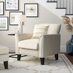 a living room with pictures on the wall and a chair next to a footstool