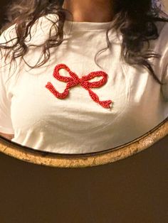 a woman wearing a white shirt with a red bow on it