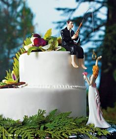 two figurines are sitting on top of a wedding cake, one holding a fishing rod