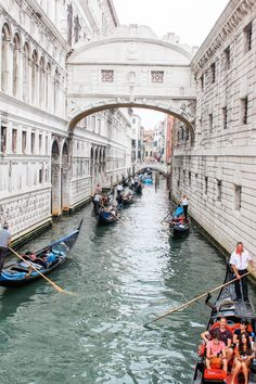 several people are riding in boats down the canal under an arched stone bridge with arches