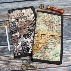 two notebooks sitting next to each other on top of a wooden table with a pair of scissors