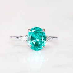 Gorgeous Paraiba Tourmaline Ring ►Made of solid sterling silver with rhodium finish (925) ►Accented With Simulated Diamonds (CZ) ►Average band width: 2 mm Center Stone: Paraiba Tourmaline Color: Turquoise Shape: Oval Measurements: 7.0 x 9.0 mm Carat Weight: 1.8 ct. (approx.) Gemstone creation: lab-grown Hardness: 7-7.5 (Mohs scale) ✓ 100% Nickel-Free ✓ Hypoallergenic ✓ Comfort Fit ✓ Free Ring Box ✓ Free USA Shipping Turquoise Three Stone Ring For Gift, Turquoise Three Stone Ring As A Gift, Elegant Green Aquamarine Rings, Topaz Promise Ring With Center Stone For May Birthstone, May Birthstone Topaz Promise Ring With Center Stone, Classic Aquamarine Rings With Accent Stones, Oval Turquoise Ring In Sterling Silver For Wedding, Green Aquamarine Ring With Center Stone, Oval Turquoise Sterling Silver Ring For Wedding