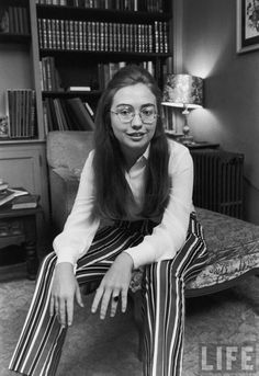 a woman sitting on the floor in front of a bookshelf