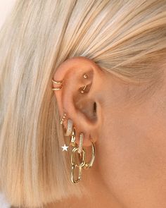 a woman with blonde hair wearing gold ear cuffs and an ear cuff in front of her ear