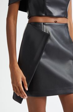 An asymmetric faux-wrap detail lends contemporary drama to this sleek faux-leather miniskirt that's sure to turn heads. 16 1/2" length (size 2) Pull-on style Lined 100% polyurethane Dry clean Imported Black Owned/Founded Sleek Faux Leather Lined Skirt, Sleek Faux Leather Skirt With Lined Detail, Fitted Faux Leather Mini Skirt Skort, Luxury Black Faux Leather Skirt, Luxury Black Leather Mini Skirt, Leather Miniskirt, Leather Mini Skirts, Fabric Gift Bags, Free Fabric