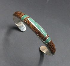 All sterling silver cuff bracelets include free engraving. Please Include your desired engraving with the order. This is a handmade sterling silver cuff bracelet with inlays of coconut wood and natural malachite stone The bracelet width is 10mm tapering to 8mm. The gap is 1.25 inch. Select your wrist measurement from the drop down menu. We will make your bracelet to fit. Please measure your wrist if you are unsure of the size. We want your bracelet to fit perfectly. Solid sterling silver and sto Mens Cuff Bracelets, Bracelet Gift Box, Silversmith Jewellery, Coconut Wood, Inlay Jewelry, Bracelet Stone, Cuff Bracelets Handmade, Malachite Stone, Stone Inlay