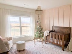 a baby's room with a crib, rocking chair and christmas tree in the corner