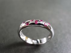 A wedding band with ruby made in 14k white gold. Product Specifications: Type: Natural Ruby Number of Gemstones: 7 Precious Metal: 14K Gold Ring Width: 3.90mm Currently made to order pieces may take up to 10 business days to complete, or let me know if you need it urgent. You may also like: A similar ring with diamond, https://www.etsy.com/listing/65904988/diamond-wedding-ring-in-14k-white-gold It's easy to create jewelry that's perfect for you. Change the materials to suit your style and budget Pink Sapphire Round Cut Jewelry For Wedding, Pink Sapphire Round Cut Wedding Jewelry, Fine Jewelry Pink Sapphire Birthstone Ring For Wedding, Pink Sapphire Gemstone Wedding Ring, Wedding Rings With Brilliant Cut Pink Sapphire, Pink Sapphire Birthstone Ring For Weddings, White Gold Pink Sapphire Ring For Wedding, Wedding Pink Sapphire Ring With Round Band, Elegant Pink Sapphire Wedding Birthstone Ring