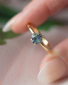 a woman's hand is holding a ring with a blue stone on the side