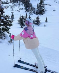 a woman riding skis down the side of a snow covered slope next to trees