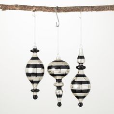 three black and white ornaments hanging from a branch