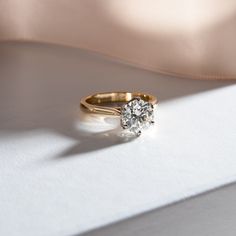 a diamond ring sitting on top of a white surface