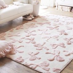 a white couch sitting next to a pink rug on top of a hard wood floor