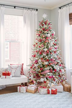 a decorated christmas tree in a living room with presents on the floor next to it