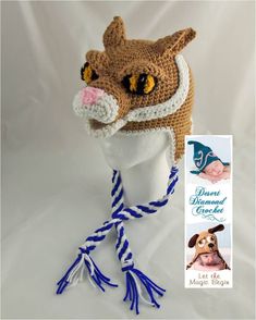 a crocheted hat with blue and white stripes on it, featuring a dog's face