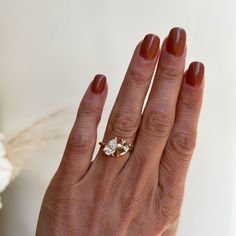 a woman's hand with a ring on it and a flower in the background