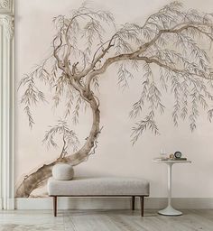 a white bench in front of a wall with a tree painted on it and a table next to it